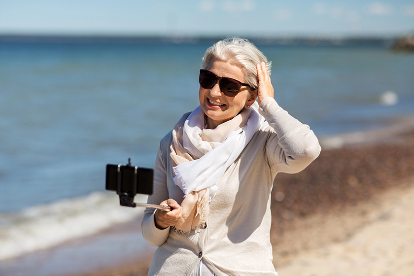 Senior woman taking selfie on beach 