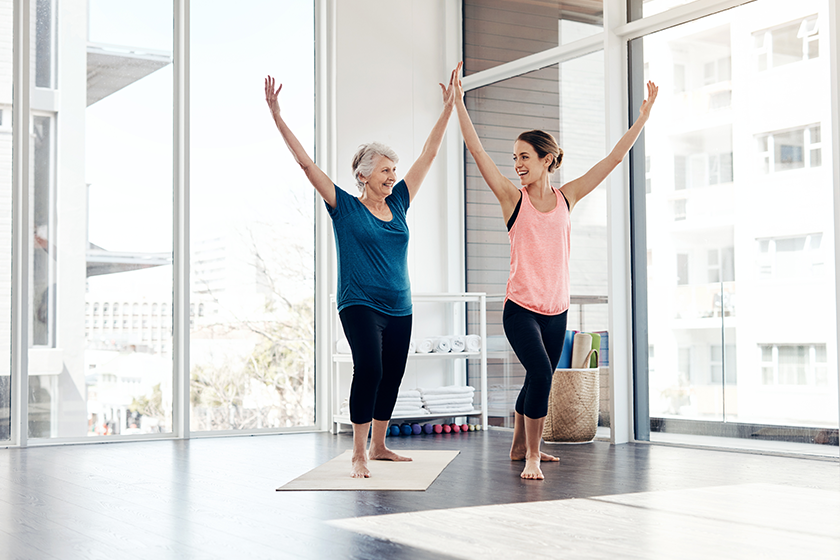 Simply follow my lead. a fitness instructor helping a senior woman yoga class
