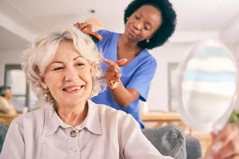 caregiver brushing the hair of senior woman