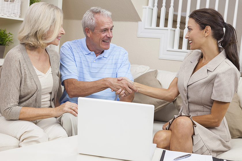 Saleswoman Shaking Hands With Senior Couple 