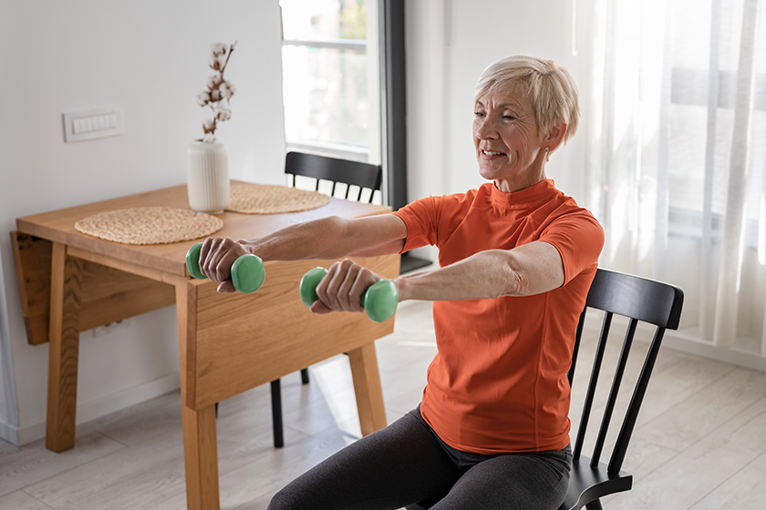 Smiling beautiful senior woman health instructor doing chair exercises